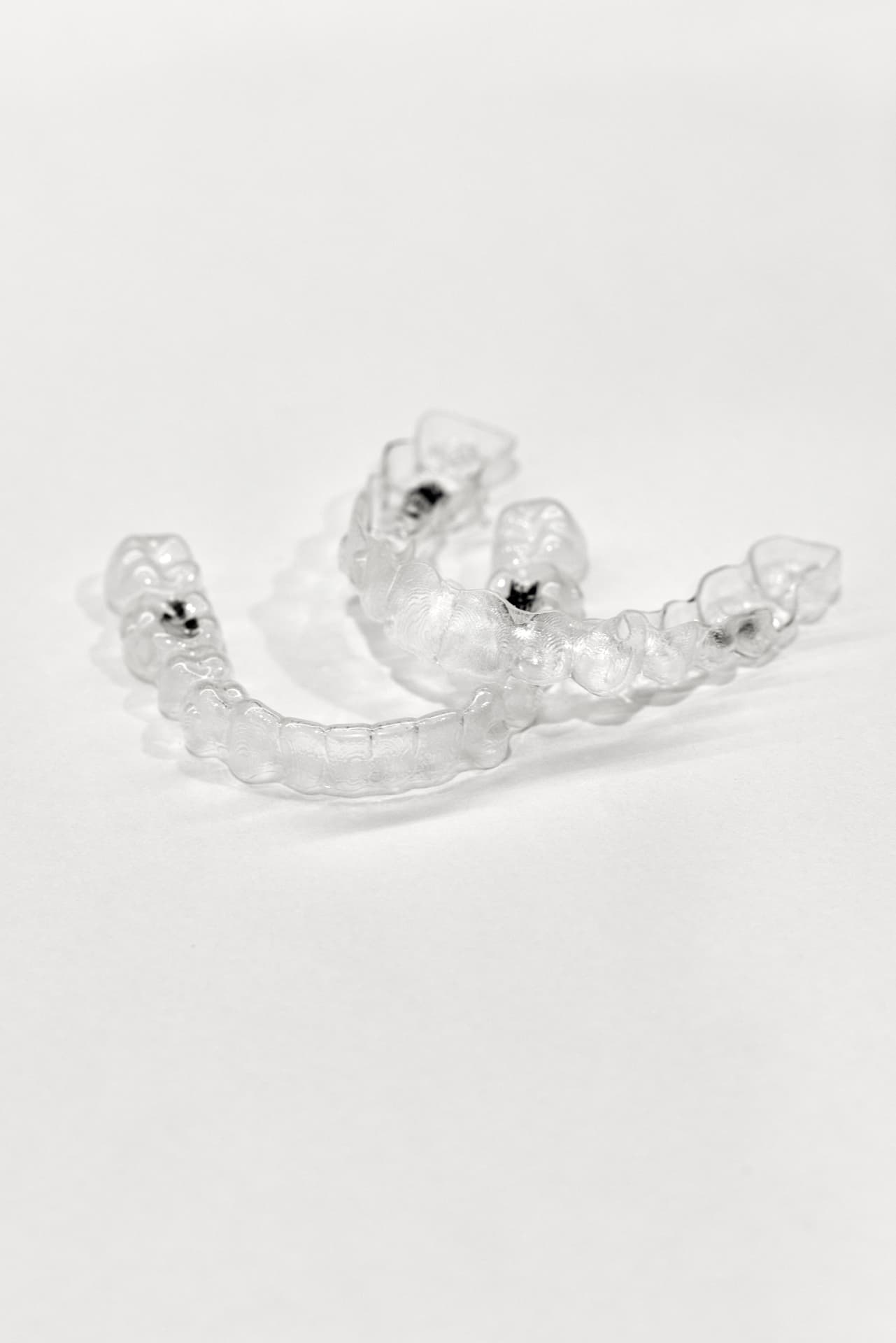 A pair of clear orthodontic aligners on a white surface