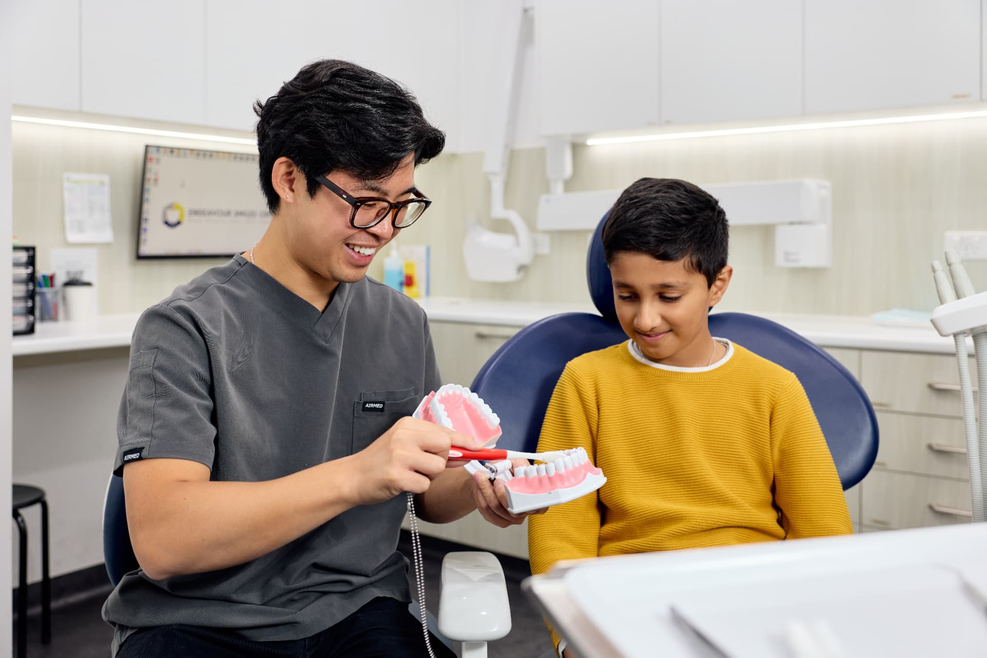 Friendly dentist showing a child how to brush their teeth